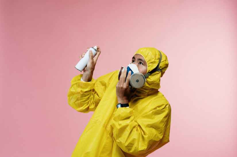person in coveralls holding spray bottle